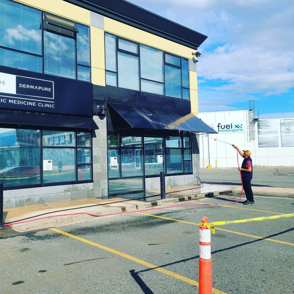 Worker pressure washing the exterior awning and windows of a Dermapure medicine clinic.