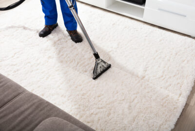 Person cleaning a white shag carpet with a professional vacuum cleaner.