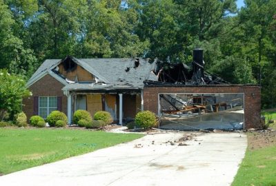 *   Image: A brick house with severe fire damage.
    *   Details:
        *   Roof is partially collapsed and charred black.