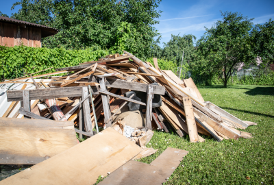 A large pile of discarded wooden boards and scrap materials sitting on a grassy lawn.