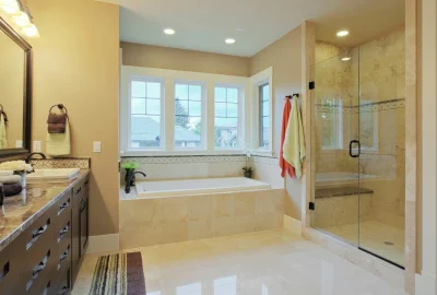 Modern bathroom with a marble vanity, soaking tub under a large window, and a glass walk-in shower.