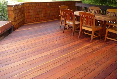 Wooden outdoor deck with a dining table and several wooden chairs.