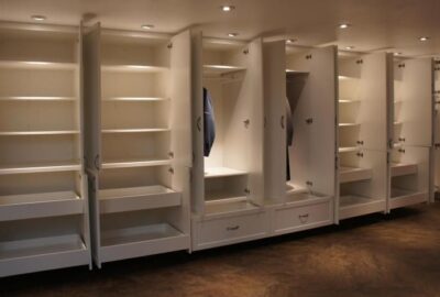 Built-in white cabinetry system with open doors revealing shelves, drawers, and hanging space.