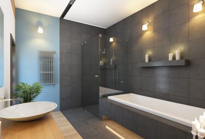 Modern bathroom with gray tiled walls, a white rectangular tub, oval sink on a wood counter, and a glass shower.