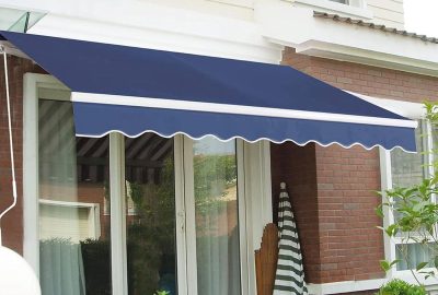 Retractable dark blue awning with white scalloped trim mounted over patio glass doors on a brick house.