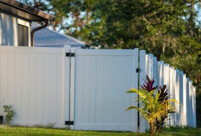 *   Image: A white vinyl fence with a gate, located in a yard.
    *   Key elements:
        *   White vinyl fence (privacy s