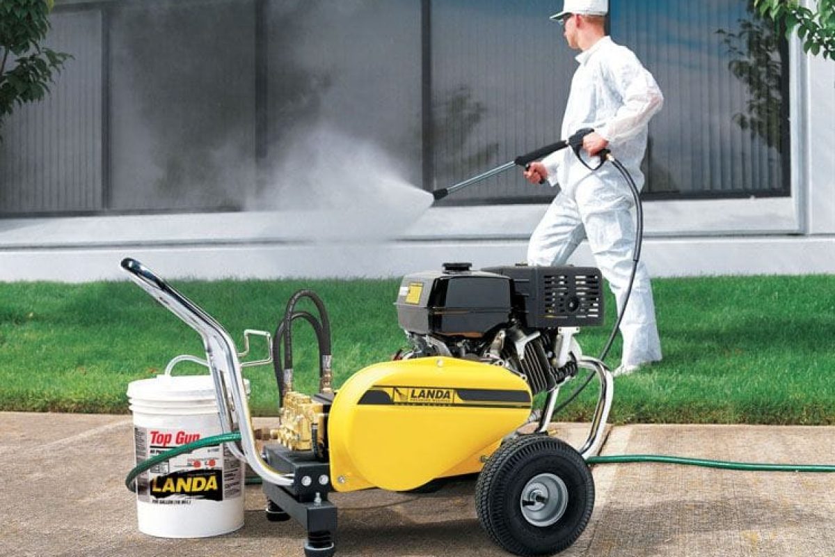 A worker using a machine to water the grass in a commercial area, ensuring proper irrigation.