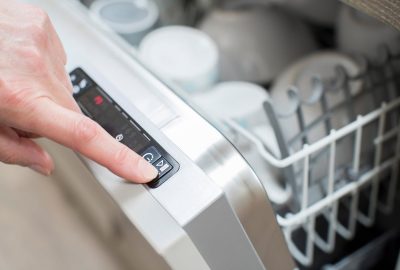 *   Image: A close-up of a hand pressing a button on a dishwasher's control panel.
    *   Key elements: Hand, finger, start/