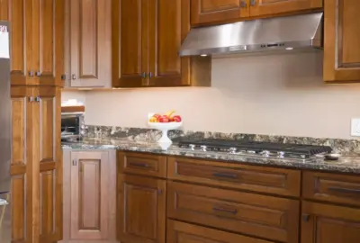 Kitchen with wooden cabinets, granite countertops, a gas stovetop, and a stainless steel range hood.