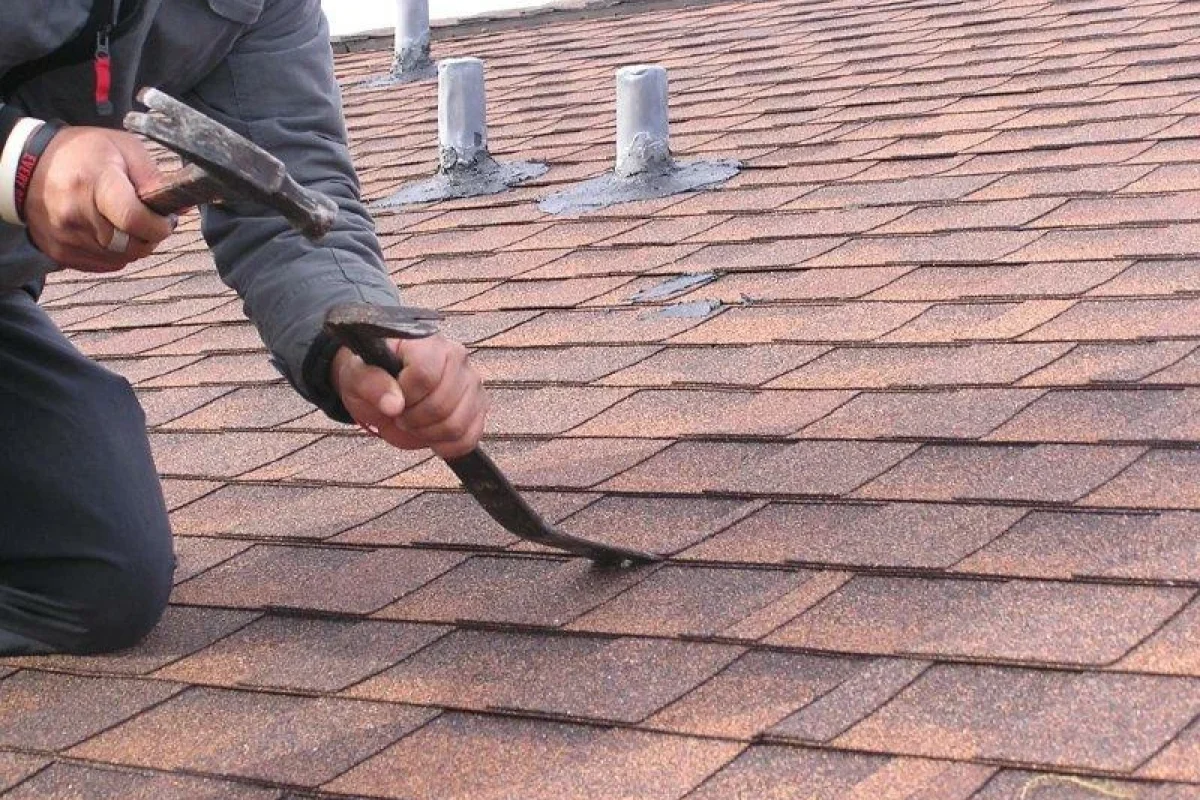*   Image: A person working on a roof.
    *   Action: Using a hammer and a pry bar (or similar tool) to remove or lift aspha