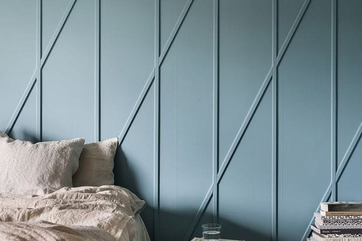 *   Image content: A bedroom scene.
    *   Key elements:
        *   Wall: Light blue/grey color, featuring a geometric wood