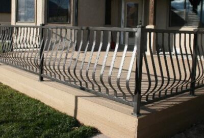 Decorative metal railing with a curved, wavy design surrounding a raised tan concrete patio.