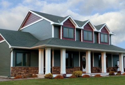 *   Image: A two-story house.
    *   Colors: Blue-grey siding, red accents on gables, white trim/pillars, dark green roof, s