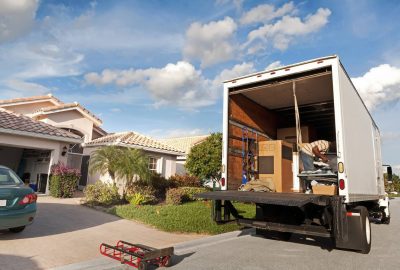 Workers loading household items into a truck in a residential area, organizing belongings for transport.