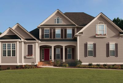 *   Image: A large, two-story suburban house.
    *   Color: Grey/taupe siding, dark brown shutters, red front door.
    *