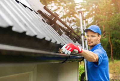 A worker cleaning a roof, focusing on areas where dirt and debris have accumulated.