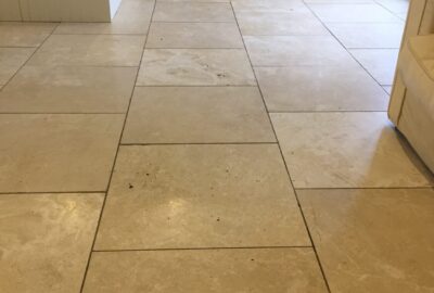 Beige stone tile flooring in an open interior space with white cabinetry.