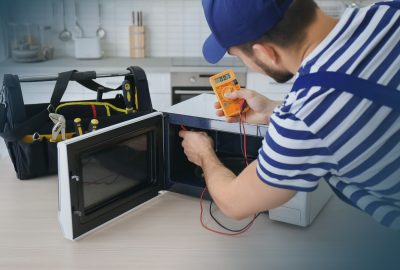 Youngmanrepairingmicrowaveoveninkitchen-Imgradient