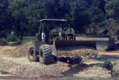 Front-end loader with a bucket full of gravel on a construction site.