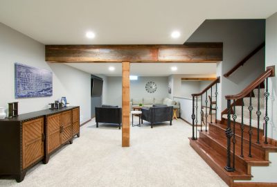 *   Image content: A modern basement living area.
    *   Key elements:
        *   Wooden support beam and post.
        *