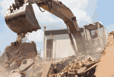 Excavator bucket dropping concrete and rebar debris onto a rubble pile during demolition.