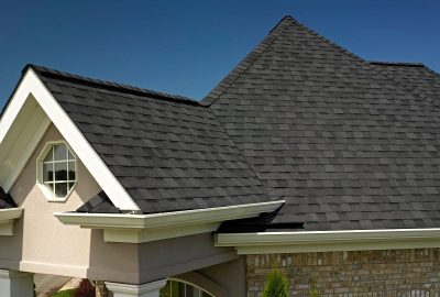 *   Image: A close-up shot of a house's roof and upper exterior.
    *   Key elements: Dark grey/black asphalt shingles, whit