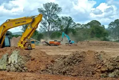 Yellow and blue excavators and heavy machinery moving earth at a construction site.