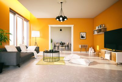 Modern living room with bright orange walls, a grey sofa, round black coffee table, and white beanbag chairs.