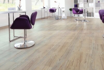 Light wood-textured laminate flooring in a modern, bright office with purple chairs and white desks.