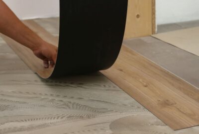 Installing wood-look vinyl flooring planks on a subfloor with adhesive.