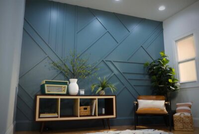 Living room with a blue geometric accent wall, mid-century modern console, leather chair, and indoor plants.