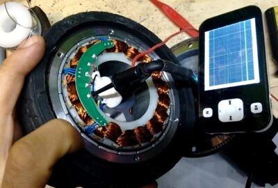 Testing a circular copper coil component using an oscilloscope probe and a handheld digital oscilloscope.