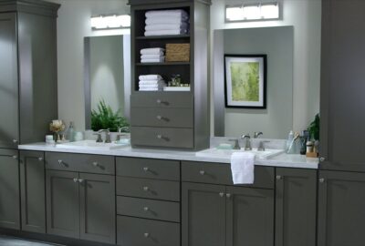 Modern bathroom vanity with grey cabinetry, white marble countertops, two sinks, and tall storage cabinets.