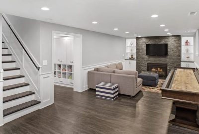 *   Image: A finished basement.
    *   Key elements:
        *   Stairs on the left (white risers, dark treads).
        *