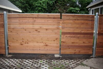 Horizontal wooden slat privacy fence and gate with metal posts.