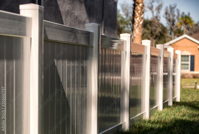 Modern fence with white posts and dark grey ribbed panels on a green lawn.