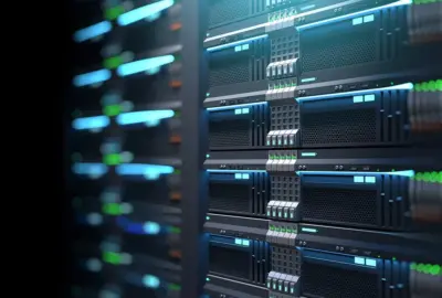 Stacked server racks in a dark data center with glowing blue and green lights.