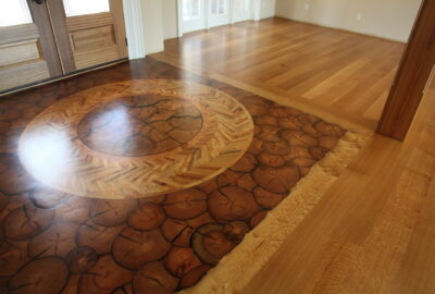 Polished hardwood floor with a large, circular inlaid medallion and wood slice patterns.