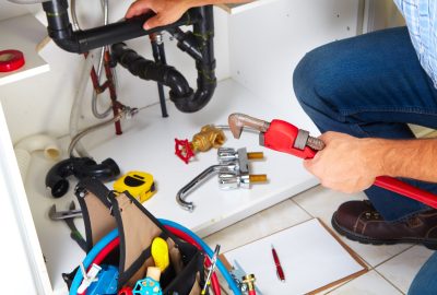 Plumber with Plumbing tools on the kitchen. Renovation.
