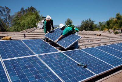 *   Image: Two workers in hard hats and safety gear installing solar panels on a tiled roof.
    *   Action: They are lifting