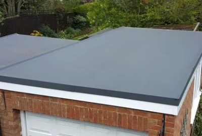 Grey flat roof membrane on a red brick garage with white fascia.