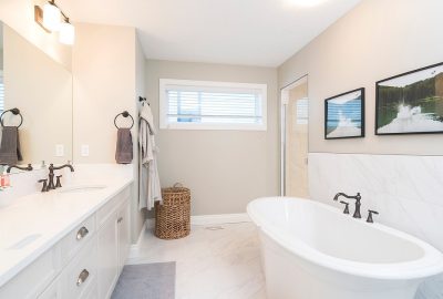 Modern bathroom with a white double vanity, a freestanding soaking tub, and light gray walls.
