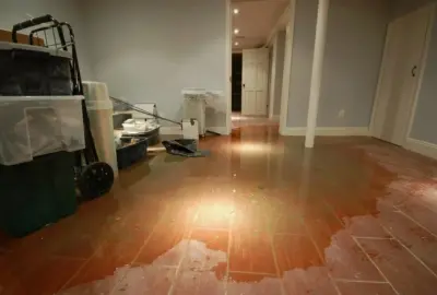 Standing water covering the brown tile floor of a storage room and extending into a hallway.