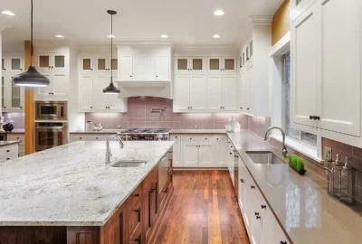 Modern kitchen with white cabinetry, marble countertops, a large center island, and wood flooring.