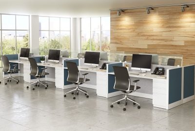 Modern open office with white workstations, black ergonomic chairs, and computers against a wood-paneled wall.