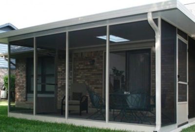 Screened-in patio attached to a brick house with outdoor furniture and a skylight.