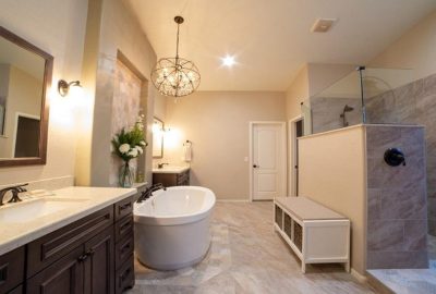 Spacious master bathroom with a white soaking tub, double vanities, walk-in shower, and crystal chandelier.