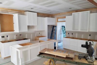 Kitchen under construction with white cabinets, an island frame, and various carpentry tools.