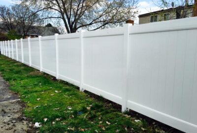 White vinyl privacy fence running along a grassy yard.