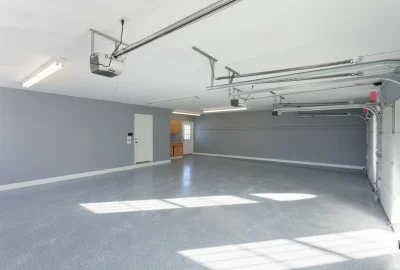 Spacious empty garage with gray walls, glossy epoxy flooring, and automatic door openers.